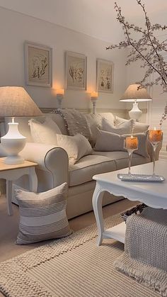 a living room filled with white furniture and lots of pillows on top of it's covers