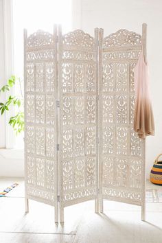 a white room divider sitting on top of a floor next to a potted plant