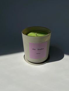 a candle with a pink sticker on it sitting on a table next to a gray wall