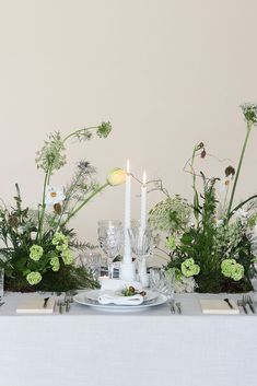 the table is set with candles, flowers and greenery for a festive dinner