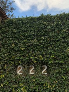 the number 22 sign is covered with green leaves and ivy on top of a building