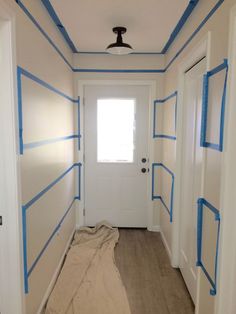 an empty room with blue tape on the walls and door painted in white, brown and blue