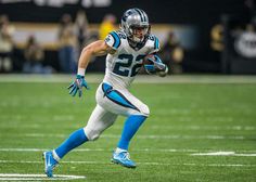 a football player is running with the ball in his hand and wearing blue gloves on