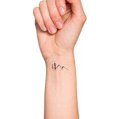 a woman's arm with a small mountain tattoo on the left side of her wrist