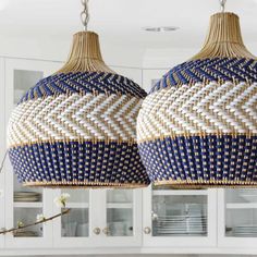 two blue and white woven lamps hanging from the ceiling in a kitchen area with cabinets