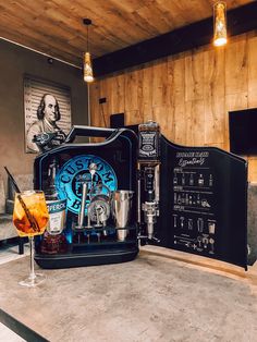 a drink machine sitting on top of a counter next to a glass filled with liquid