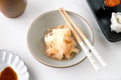 two chopsticks in a bowl with some food on the plate next to it