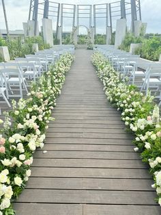 an outdoor ceremony with white chairs and flowers on the aisle, set up for a wedding