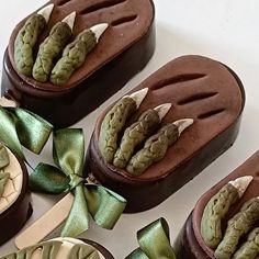 four pieces of chocolate with green decorations on them and bows tied around the edges, sitting next to each other