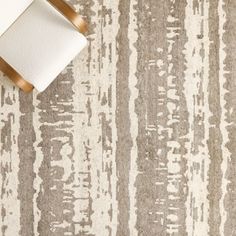 an area rug with white and brown stripes on it, next to a roll of toilet paper