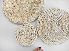 three pieces of woven rope sitting on top of a white table next to a person's hand