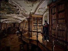 a man standing in the middle of a library filled with lots of bookcases