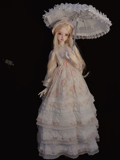 a doll dressed in white holding an umbrella