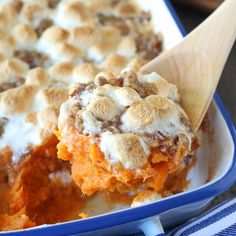 a casserole dish with marshmallow toppings and a wooden spoon in it