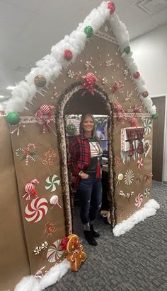 a woman standing in front of a gingerbread house