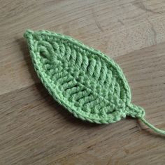 a green crocheted leaf sitting on top of a wooden table