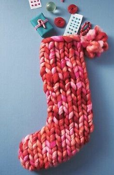 a knitted christmas stocking with buttons and other items around it on a blue background