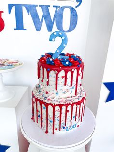 a red, white and blue two tiered cake with stars on the top is displayed