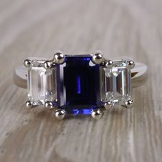 a three stone ring with an emerald and sapphire