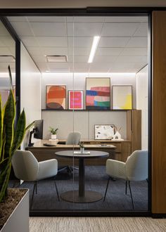 an office cubicle with two chairs and a table in front of the glass door