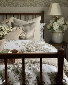 a bed with white flowers and pillows on top of it next to a night stand