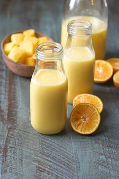 two jars filled with orange juice next to sliced oranges