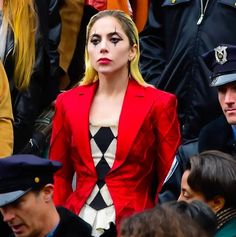 a woman in a red jacket and hat standing next to other people