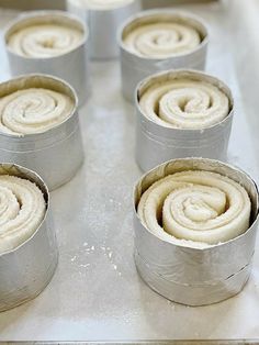 several tins filled with white frosting sitting on top of a metal pan covered in icing