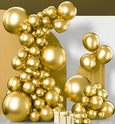 gold balloons and presents are in front of a white wall with a golden design on it