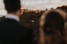 a man and woman looking out over the mountains at an airplane flying in the sky