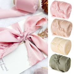 three rolls of toilet paper with pink bows on them and one rolled up in different colors