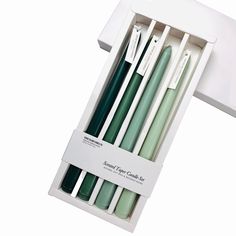 four green and white candles in a box with labels on the top one is empty