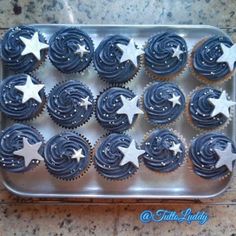 cupcakes with blue frosting and white stars on them in a tin tray