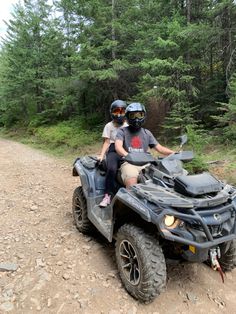 two people riding an atv on a dirt road