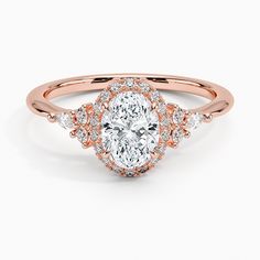 a rose gold engagement ring with an oval cut diamond surrounded by small round brilliant diamonds