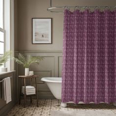 a bathroom with a bathtub, sink and shower curtain in purple colors on the wall