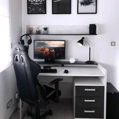 a black and white desk with two pictures on the wall above it, along with a chair