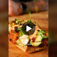 a piece of bread with cucumbers and sauce on it sitting on a cutting board