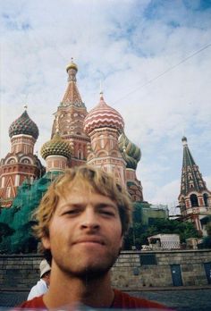 a man standing in front of a large building with domes on it's sides