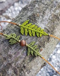 two necklaces with green leaves and beads on a tree branch in the woods,