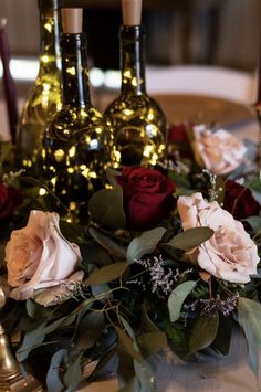 roses and candles are sitting on a table with wine bottles in the backround