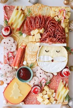 an assortment of cheeses, meats and other food items on a white surface