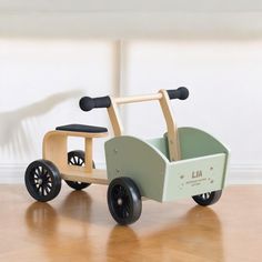 a wooden toy car sitting on top of a hard wood floor next to a white wall