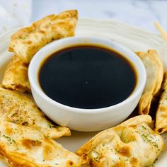 some food is on a white plate with a black sauce in the bowl and dipping sauce