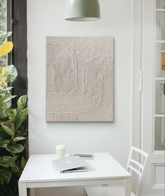 a white table with a laptop on it next to a lamp and potted plant