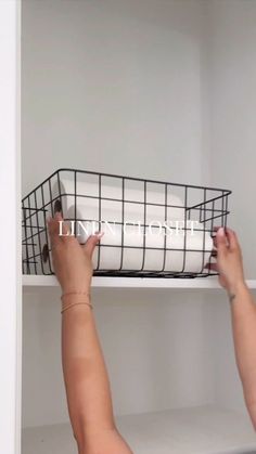 a person reaching for a basket on top of a white shelf in a room with shelves