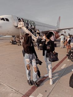 two women walking towards an airplane on the tarmac