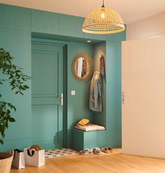 a room with a green wall and wooden flooring next to a potted plant