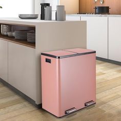 a pink trash can sitting on top of a wooden floor next to a kitchen counter