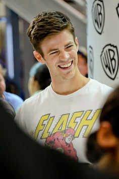 a young man smiles as he stands in front of a sign with the word flash on it